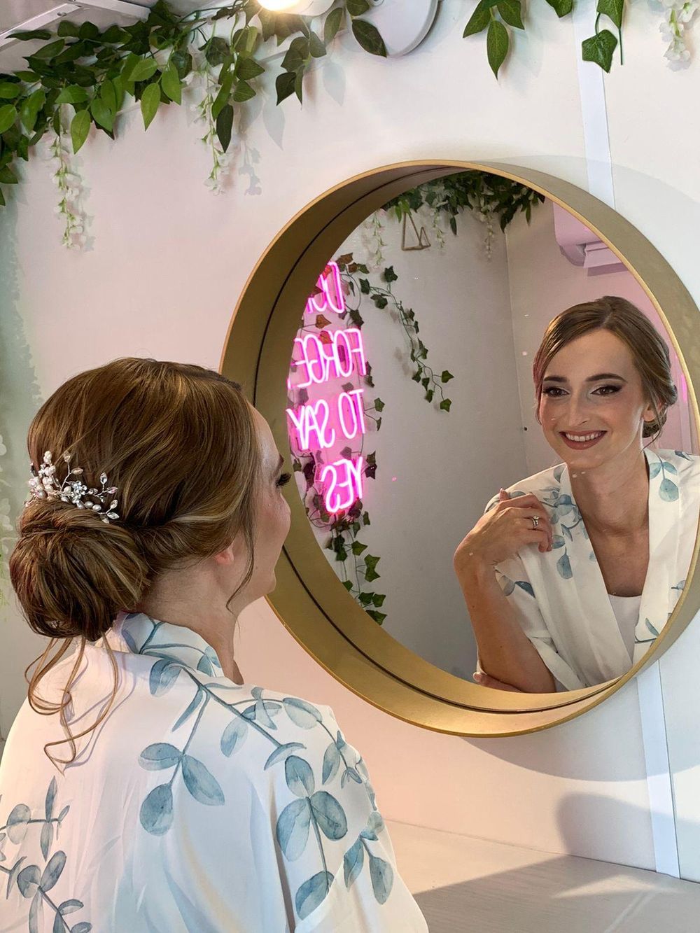 A bride looking into the round mirror with her hair and makeup finished
