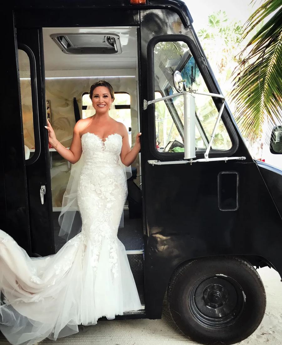 A bride in a lace gown stepping down from the Beauty Truck